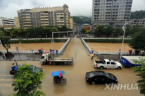 중국 서부 충칭시의 우시현에서 1일 폭우로 불어난 물 속을 차량이 운행하고 있다.