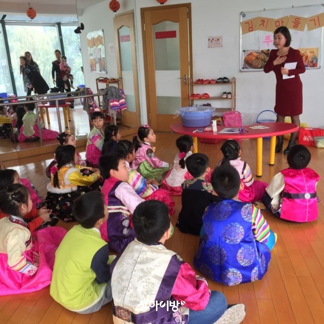 한복을 곱게 차려입은 아이들이 선생님의 김치 문화에 대한 설명을 집중해서 듣고 있습니다. 