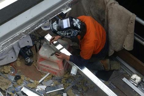 지붕 패널 조각들 사이에서 일하는 호주 퍼스 병원 건설 현장의 노동자